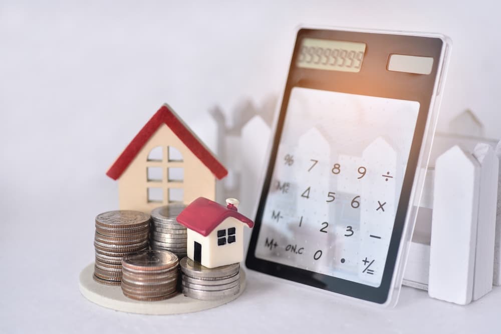 calculator and house model on a white background, considering the additional information of "loan against property in Dubai": "Illustration of a calculator and house model, representing loan against property in Dubai.